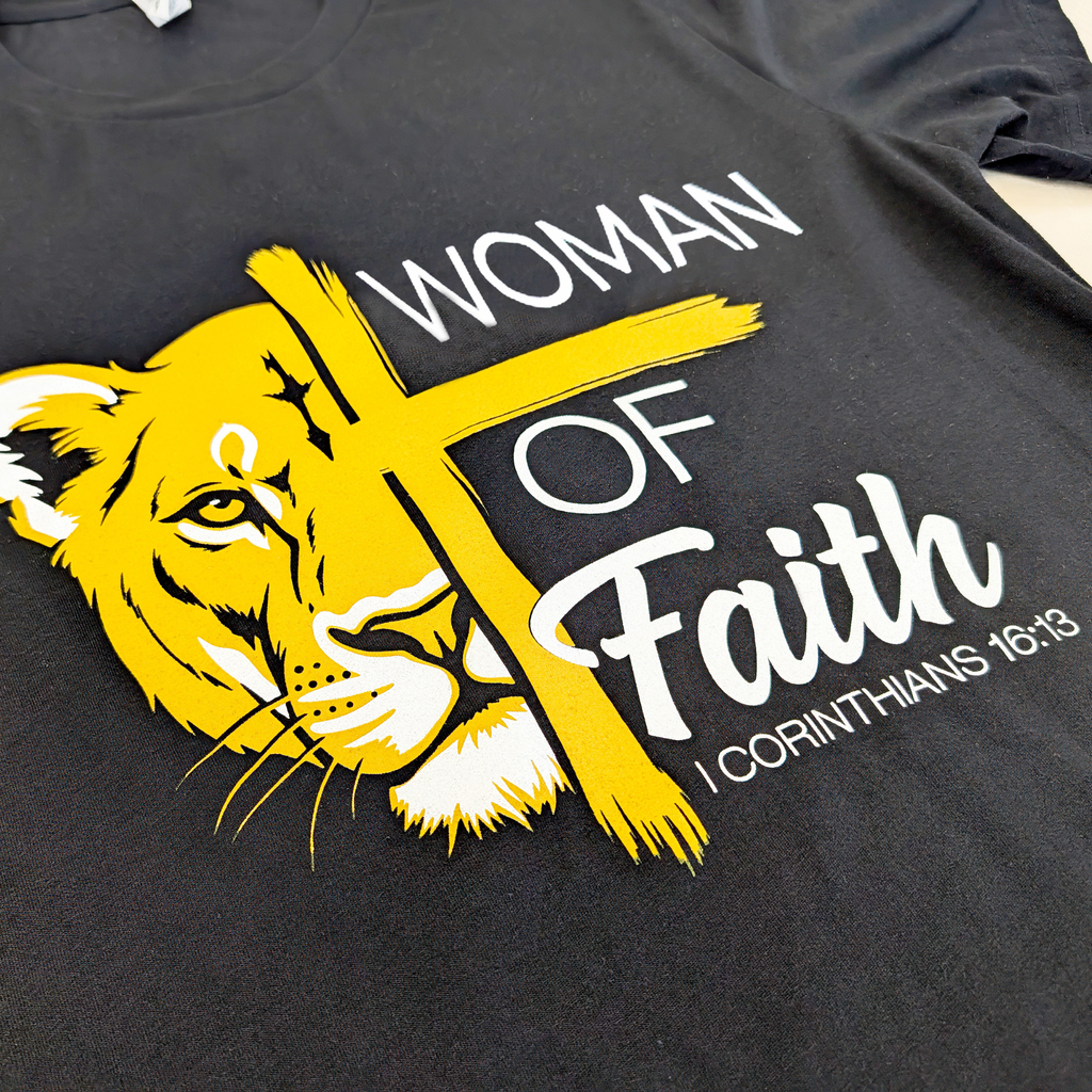Black t-shirt with yellow lion graphic and 'Woman of Faith' text on a plain background